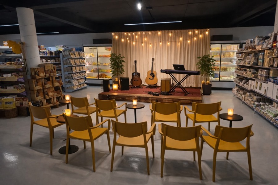 Noite de música dentro da loja: cadeiras amarelas em roda, velas nas mesas e guitarras no palco